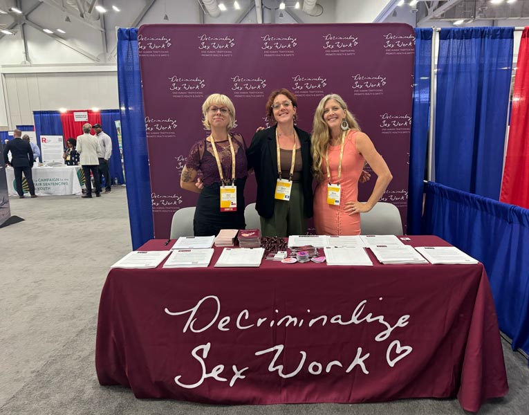 DSW Community Engagement Consultant Henri Bynx, Staff Attorney Becca Cleary, and Legal Director Melissa Sontag Broudo pose in front of DSW’s booth at NCSL